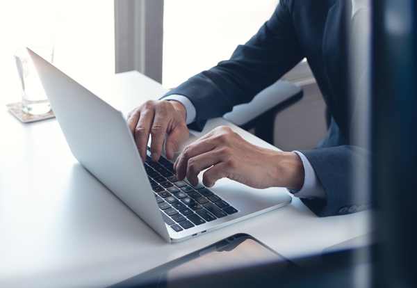 person in a suit typing on a laptop demonstrating effective work habits for success with 10 strategies for productivity