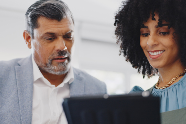two professionals discussing project details on a tablet with a focus on collaboration and innovation